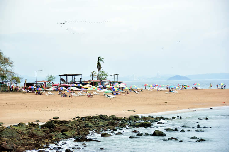 Beach with tourists under umbrellas in Taboga, Panama